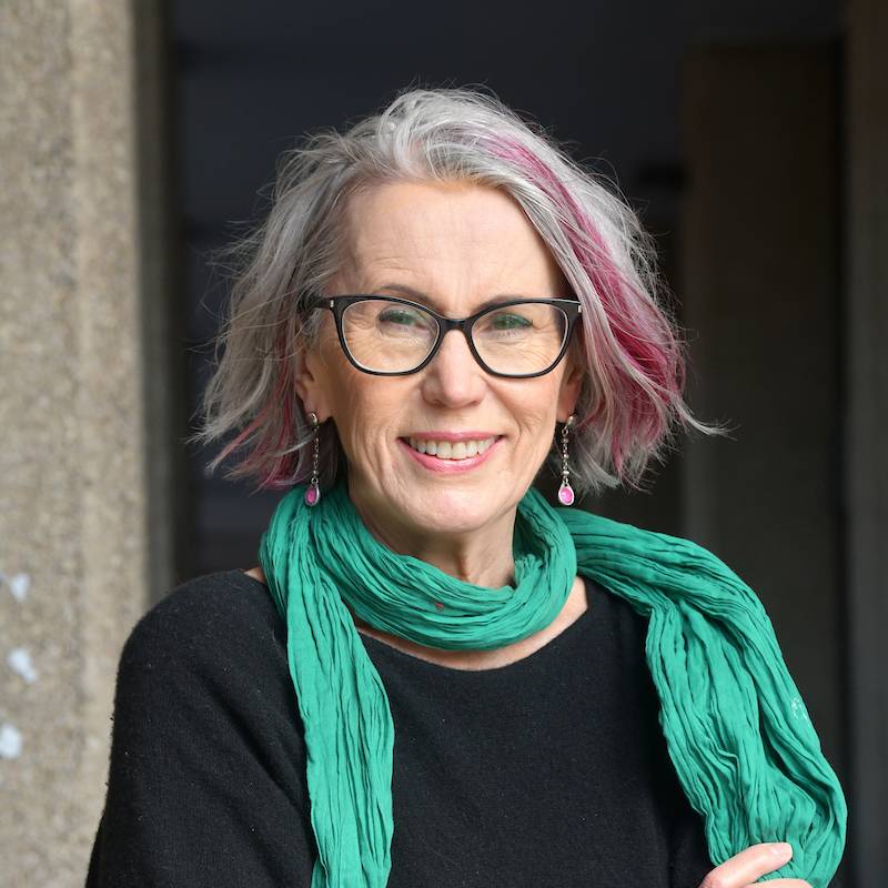 Nainen hymyilee, vihreä huivi kaulassa.