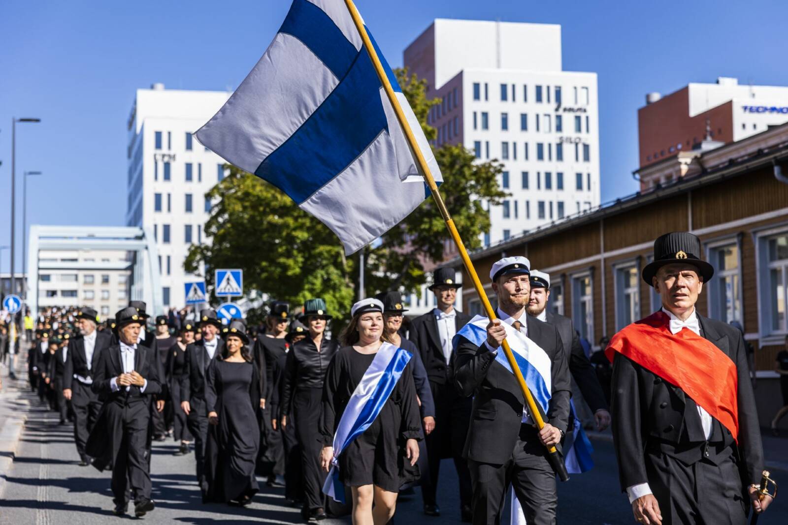 Kulkue kävelee kadulla, Suomen lippu liehuu