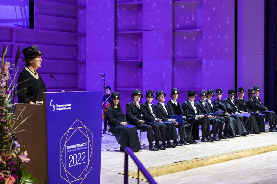 Honorary doctors sit on the stage, one of them is giving a speech