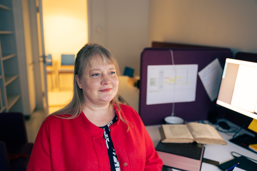 Raisa Toivo työhuoneessaan, pöydällä vanha kirja.