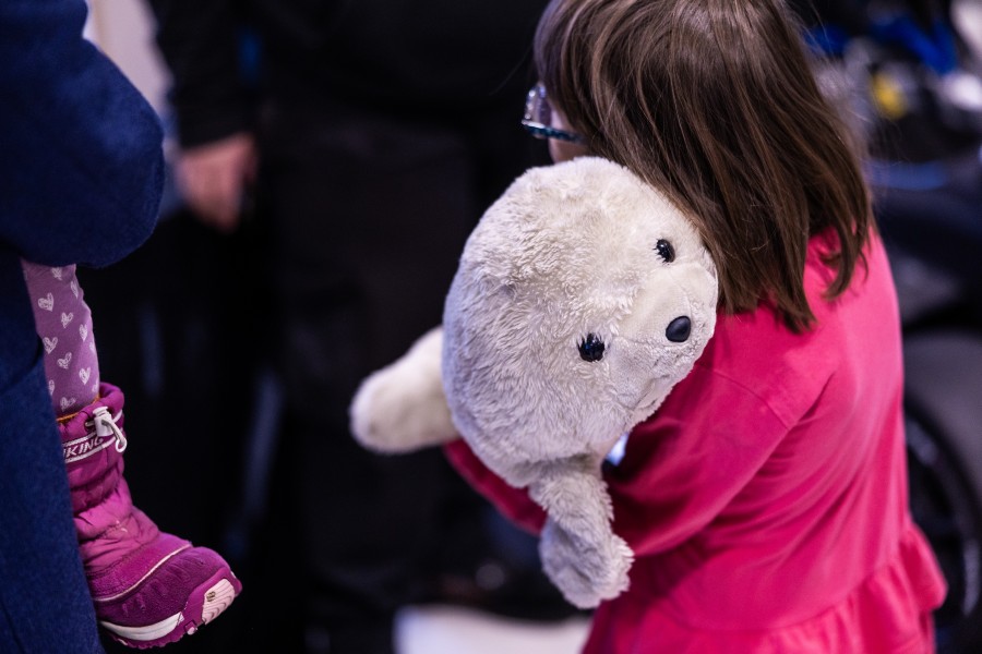 Pehmolelu nojaa punapuseroisen lapsen olkaa vasten.