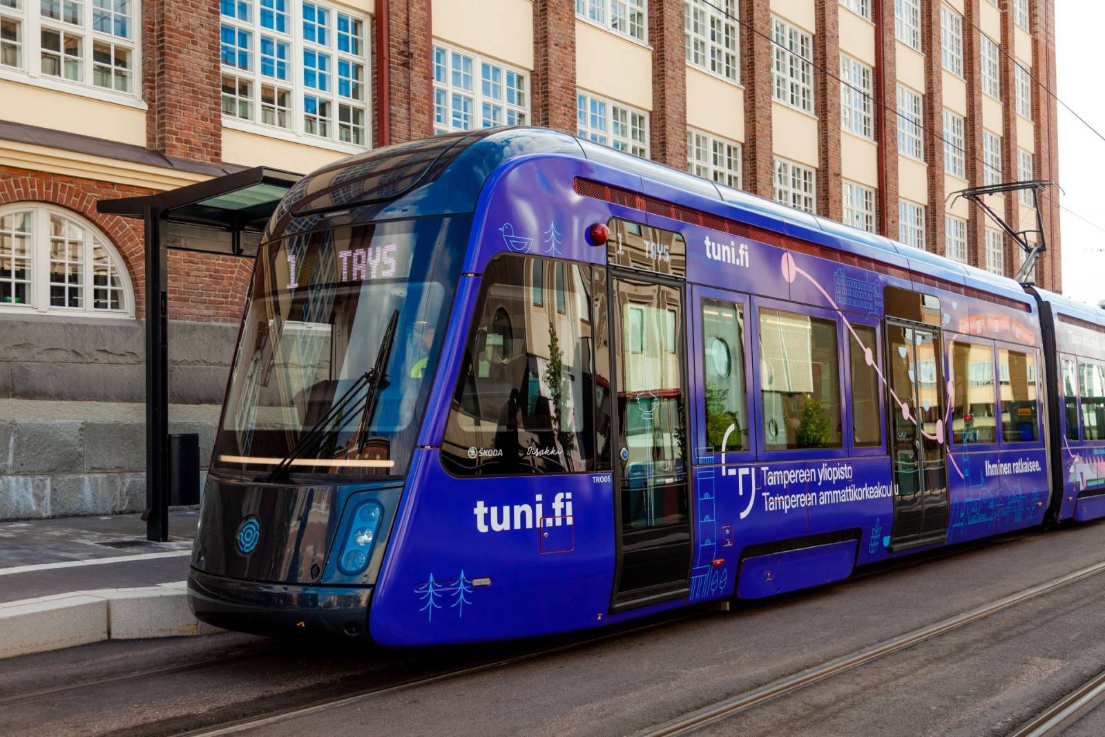 Tampereen korkeakouluyhteisön violeteilla bränditeippauksilla teipattu raitiovaunu