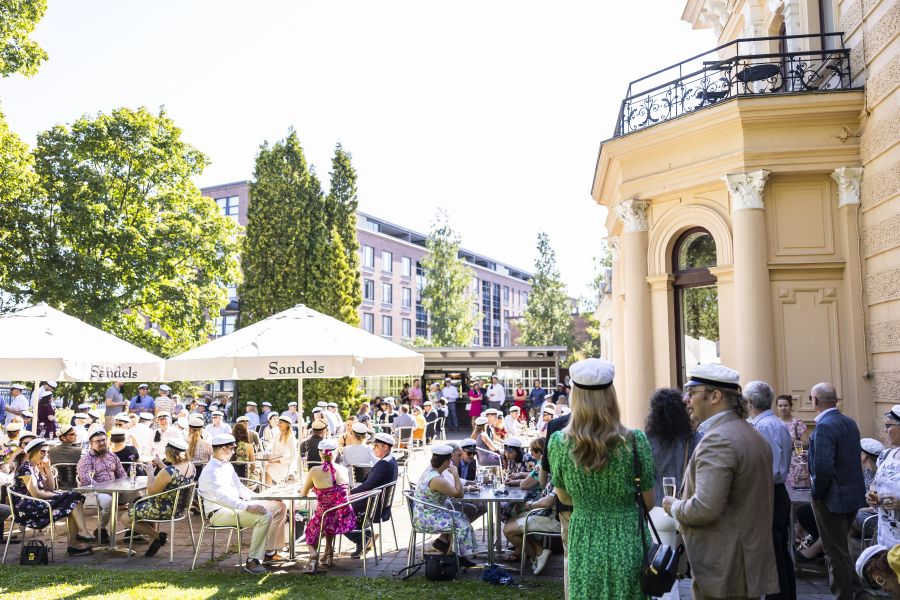 Ihmisiä kesäisissä vaatteissa puutarhajuhlissa