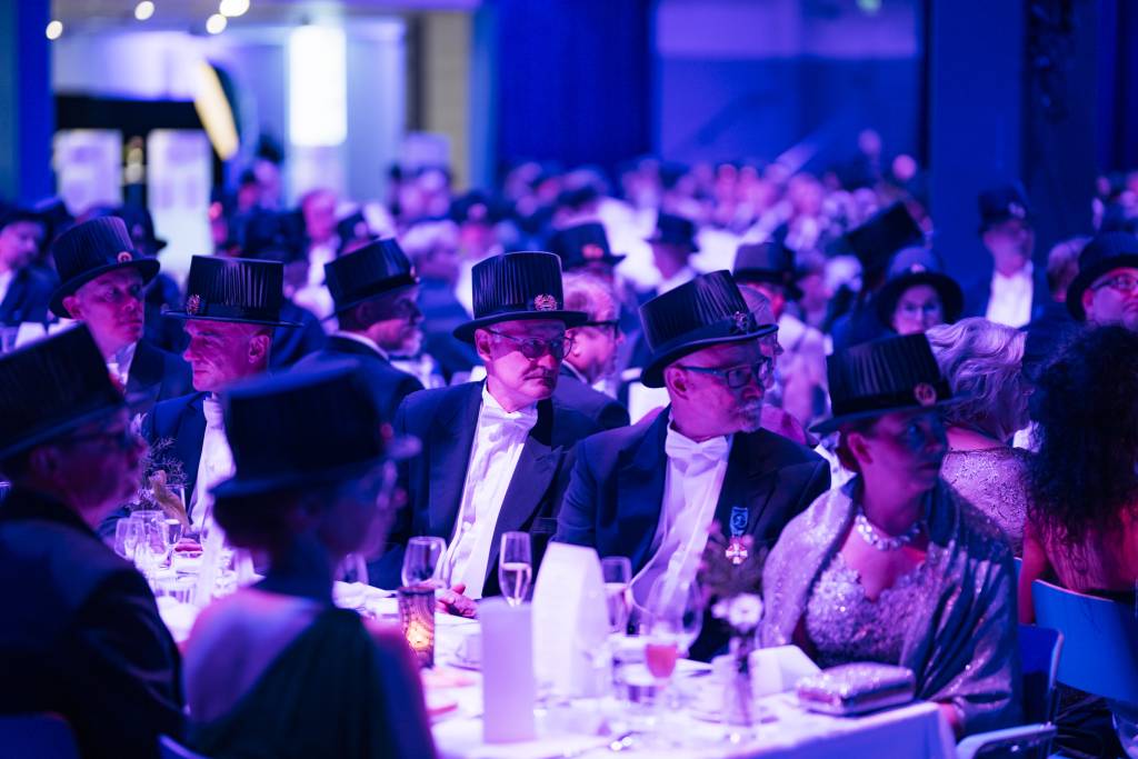 People with doctoral hats are stting at banquet tables