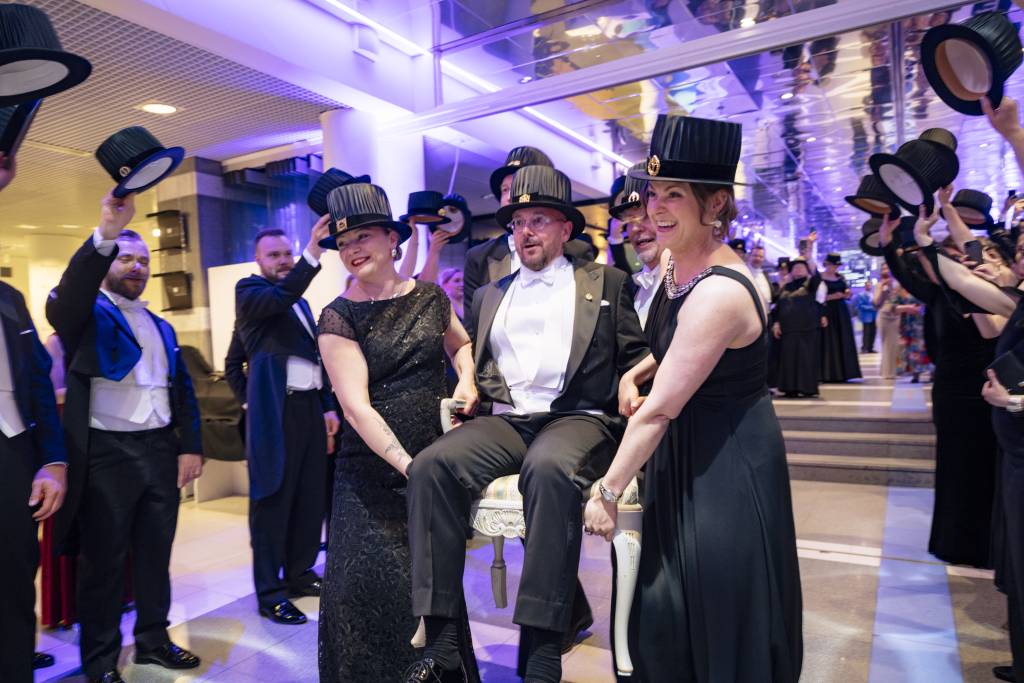 Doctors are carrying the Conferrer of Degrees in a chair