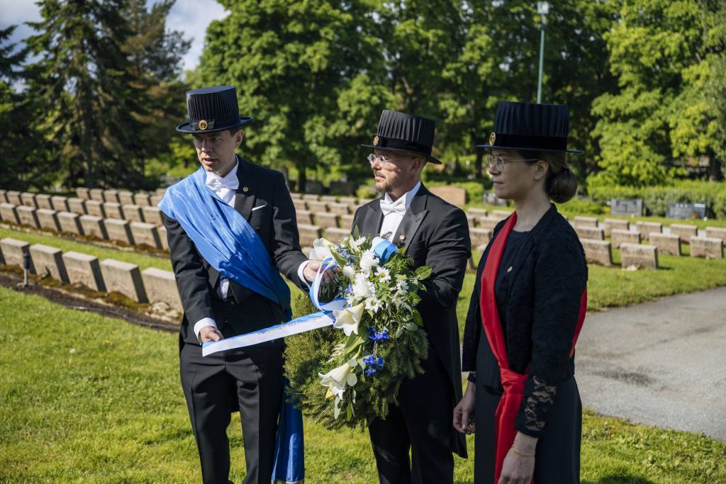 Three people are reading the text from a wreath