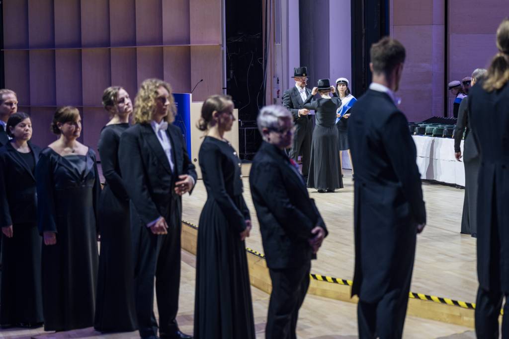 A doctor is recieving her doctoral hat while others are queueing for their turn